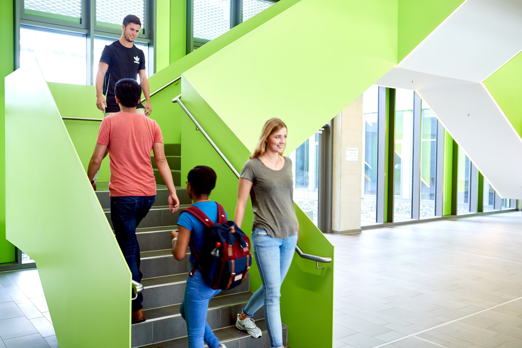 Studierende gehen eine grüne Treppe im Uni-Gebäude herauf und runter